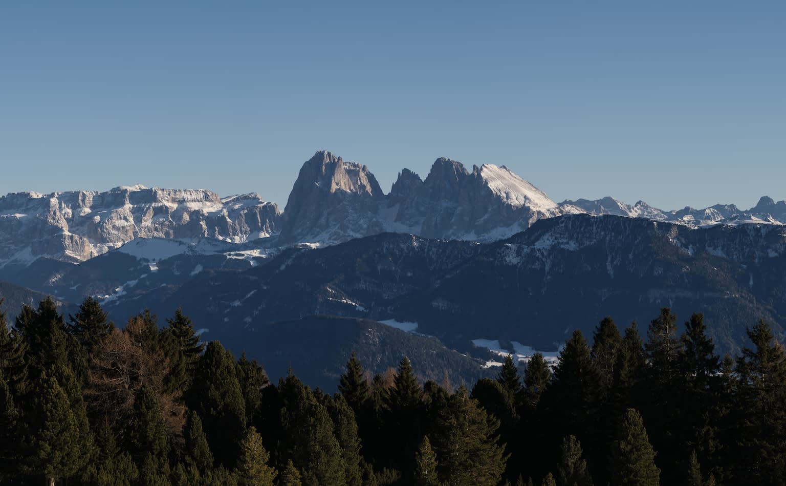 The Langkofel Group from the Villanderer Alm during the day, sunlight reflecting from one side of the mountains