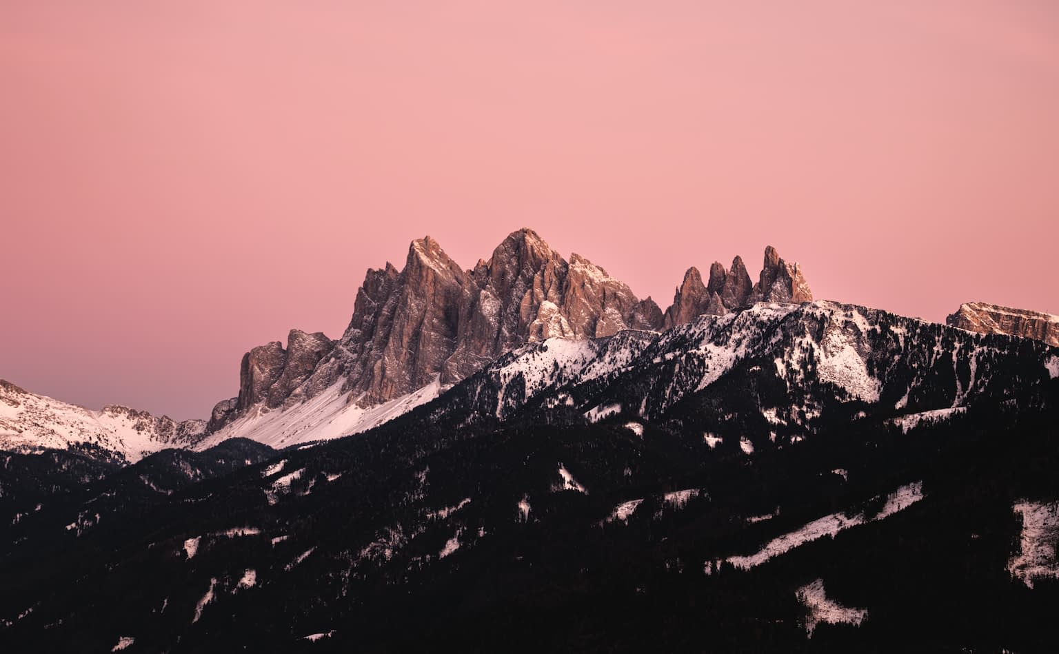 The Geisler Group from the Villanderer Alm during sunset with deep red-pink colors across the sky and mountain ranges