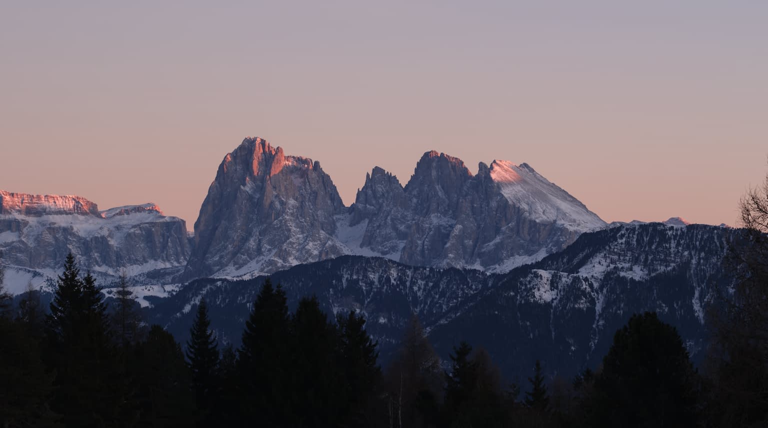 The Langkofel Group during sunset from the Villanderer Alm with hot red light peeks contrasting against the cold shadows on the mountain range