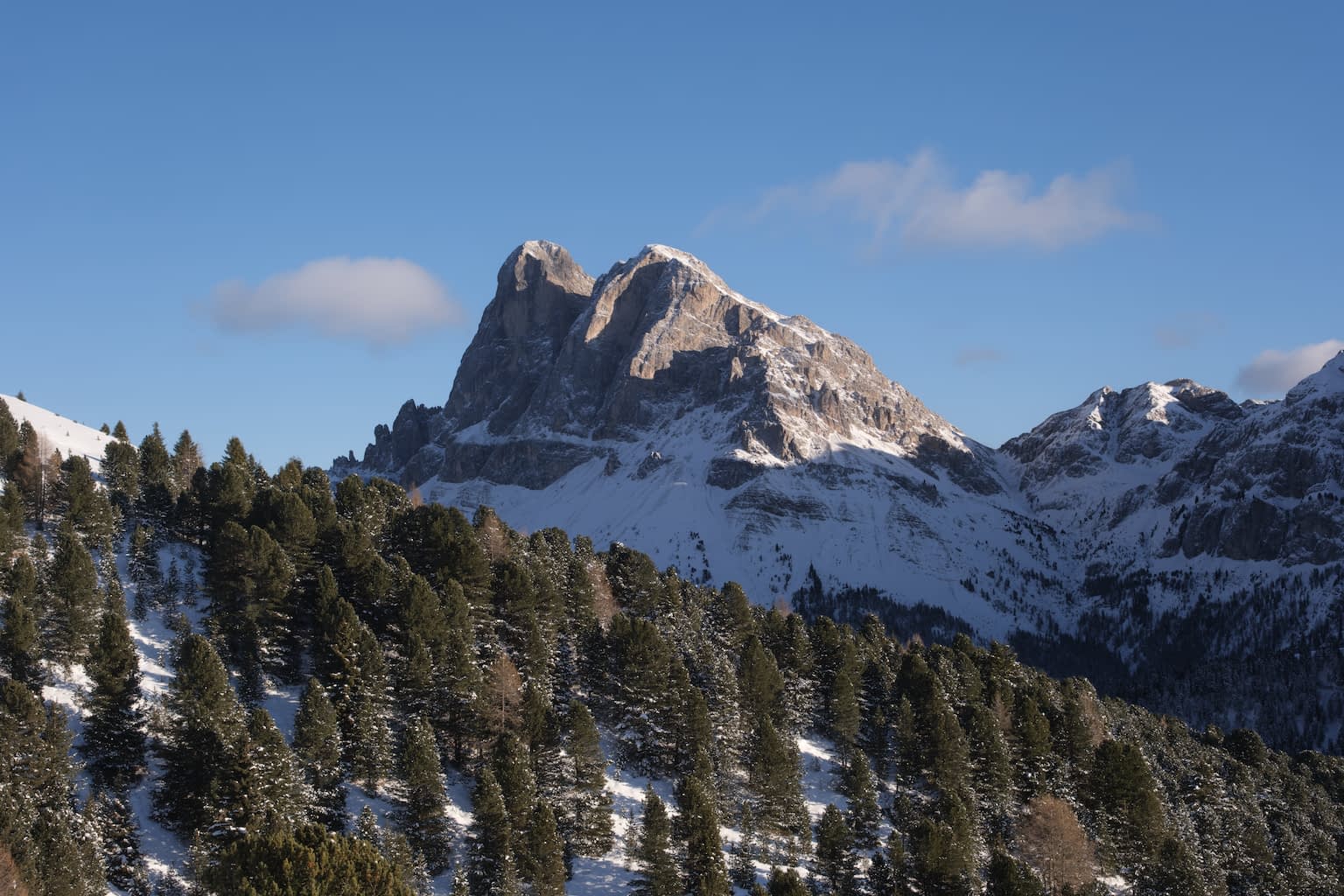 The Peitlerkofel from Afers with a cool blue sky and a hint of an early sunset reflecting off of the rook with trees and snow in the foreground