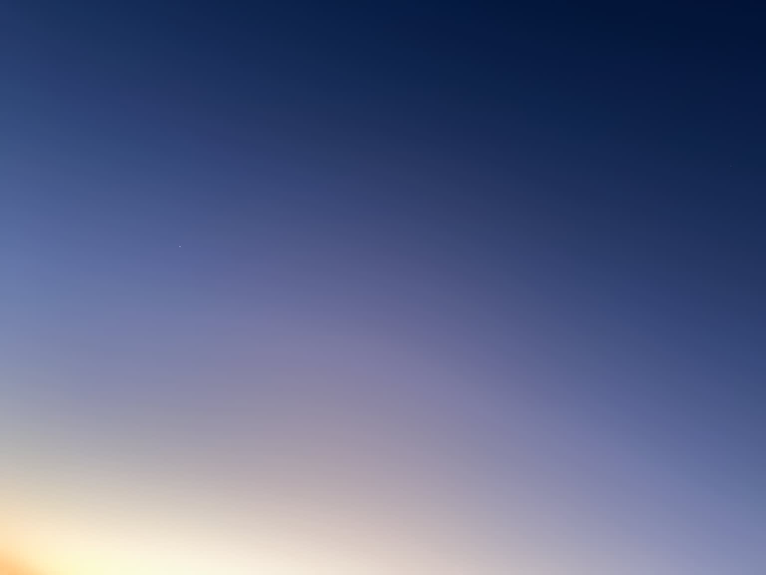 The twilight sky spanning a gradient from deep blue to pale blue to hot yellow shading from top right to bottom left with a single white dot in the center left representing the planet Venus.