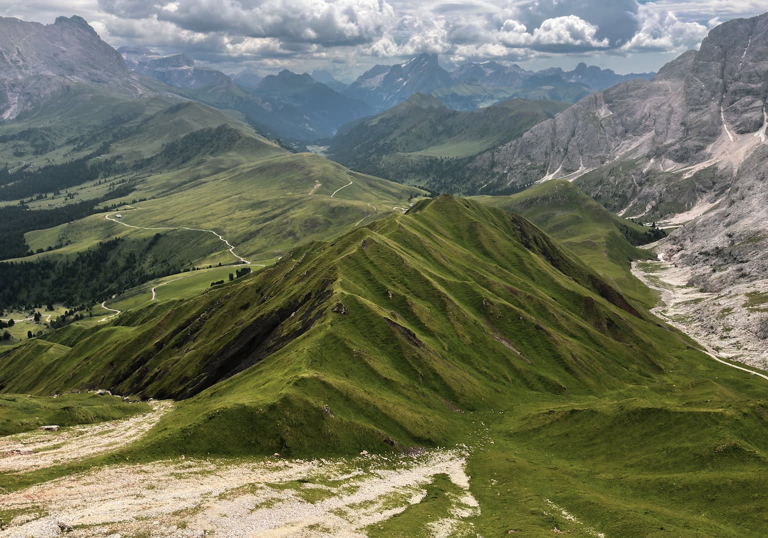 A green hill surrounded by mountains on an overcast day as seen from the Rosszahnscharte.