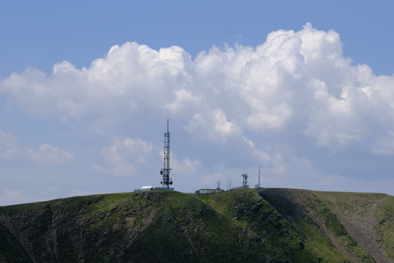 The Telegraph peak of Plose with a blue sky and large white clouds