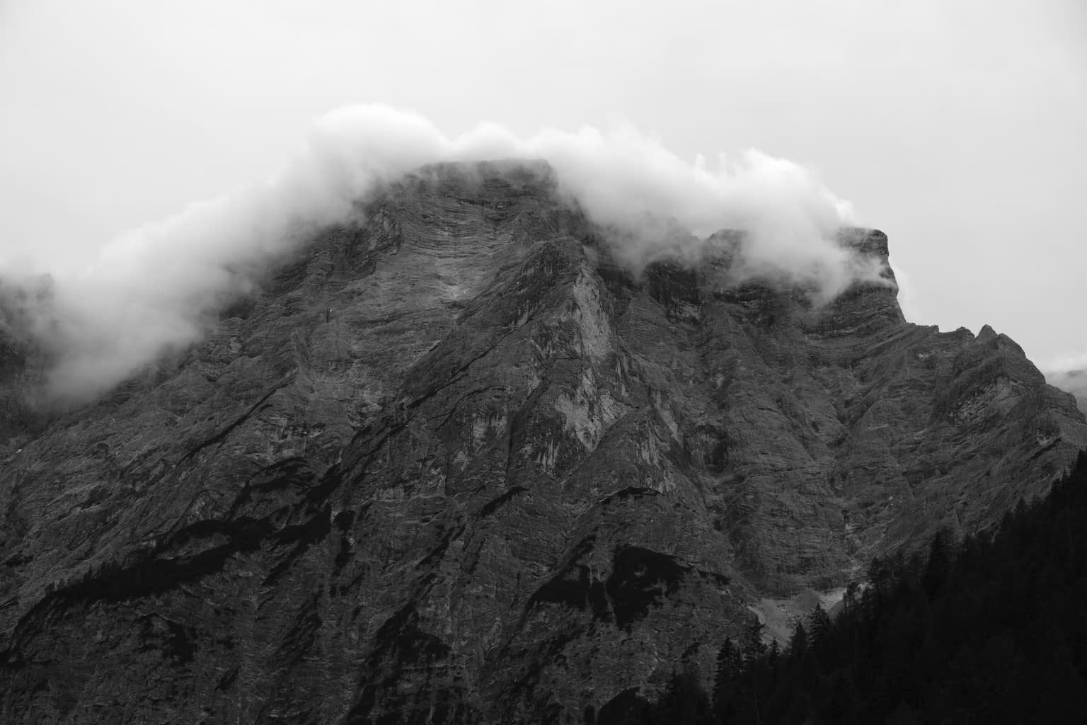 Grayscale image of the Sas dla Porta peak with a band of clouds along the mountain crest.